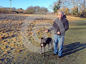 Man with greyhound dog on a leash.