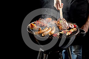 Man grilling meat on a portable barbecue