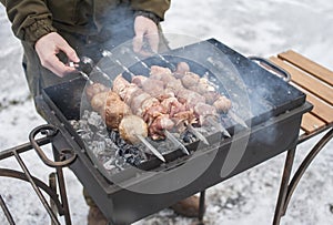 A man grills meat and mushrooms in winter. close-up. Winter picnic, outdoor recreation