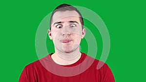 man grimaces at the camera while standing against the background of a green chroma key
