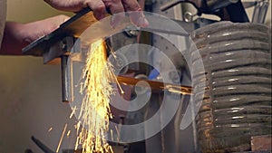 Man grinding handmade metal knife on abrasive machine with sparks, bottom view