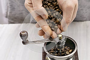 Man grinds coffee beans in a manual coffee grinder hands fall asleep grain in the coffee grinder