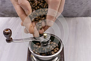 Man grinds coffee beans in a manual coffee grinder hands fall asleep grain in the coffee grinder