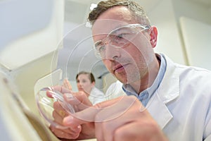 Man grinds lens into eyeglass frame photo