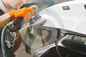 Man grinds white car after painting, close-up.