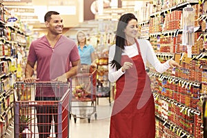Man In Grocery Aisle Of Supermarket With Sales Assistant