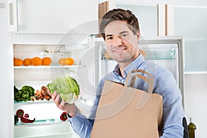Man With Grocery Bag Standing Near The Open Fridge