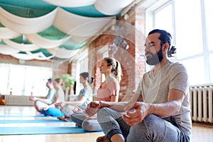 Man with group of people meditating at yoga studio