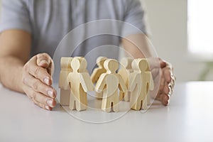 Man protecting wooden figures like corporate leader protecting team of his employees