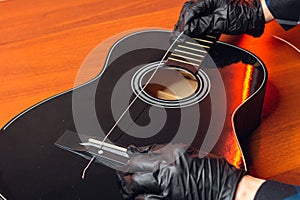 man with guitar,master hands in gloves puts on new strings .repair of musical instruments