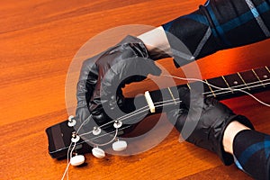 man with guitar,master hands in gloves puts on new strings .repair of musical instruments