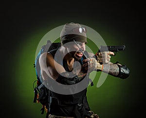 A man with a gun and a backpack on a dark background with emotions looking, aiming, watching, sneaking