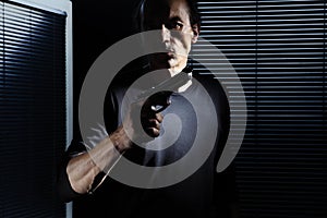 Man with gun  on black door window, policeman, detective, bodyguard and self defense concept, otherwise robber, murderer