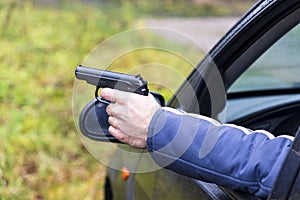 Man with a gun driving a car, male hand with a gun