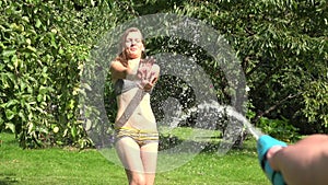 Man guy hand spray water from hose at hot woman girl in garden yard. 4K