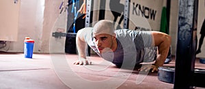 Man in gym doing push ups, panorama