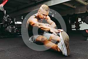 Man at the gym doing stretching exercises on the floor.Sports man at the gym doing stretching legs exercises