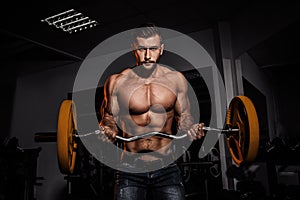 Man in gym. Muscular bodybuilder guy doing exercises with barbell. Strong person. Sports background. Young athlete ready