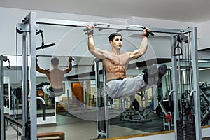 Man in gym training at crossbar, lifting up