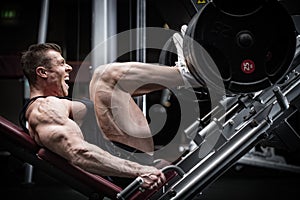 Man in gym training at leg press