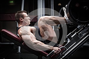 Man in gym training at leg press