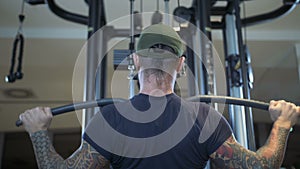 Man in the gym trains the latissimus dorsi by the lat pulldown machine