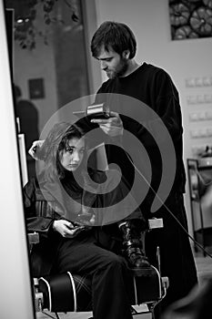 man hairdresser dries female hair with hairdryer after washing