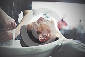 Man in a hairdresser enjoys the process of washing his head