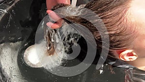 A man hairdresser washes woman's hair after dyeing her hair. Close-up