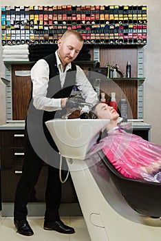 Man hairdresser washing head client the shampoo off a client`s head