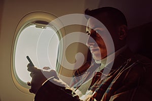 A man in a half-empty plane with a phone. Guy traveler looking at smartphone