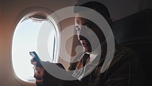 A man in a half-empty plane with a phone. Guy traveler looking at smartphone