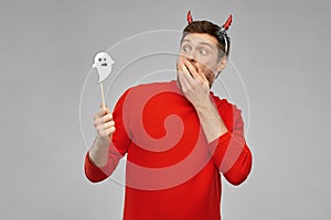 Man in halloween costume of devil over grey