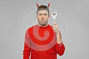 Man in halloween costume of devil over grey