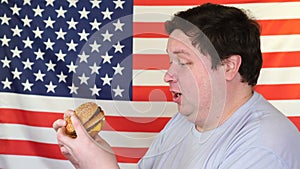 Man with a hamburger with an American flag background. Big guy wants fast food