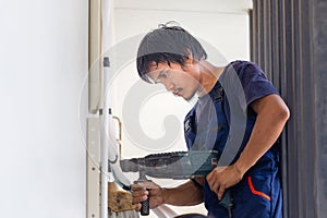 Man with hammer drill making hole in wall, Technician man installing an air conditioning in a client house, Young repairman fixing