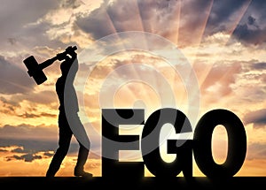 Man with a hammer in his hand intends to destroy the word ego photo