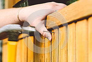 Man hammer nail into plank repairing wooden wall. Blurred motion composition