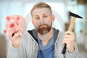 man with hammer and piggy bank looking regretful