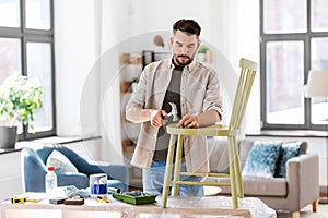 man with hammer repairing old wooden chair at home