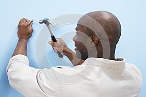 Man Hammering Nail Into Wall