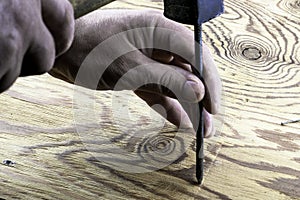 The man hammers a nail into a damaged surface