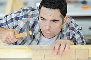 Man hammers wooden pin into furniture board