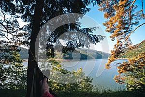 Man in hammock, first person look view, warm summer day, pine tree. river and mountains background. Travel and vacation, tourism