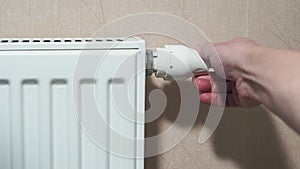 Man hand adjusting temperature thermostat on radiator.