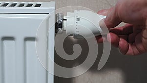 Man hand adjusting temperature thermostat on radiator.