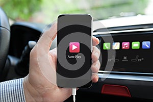 Man hand in car holding phone with app Auto Play