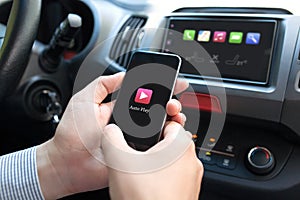 Man hand in car holding phone with Auto Play multimedia