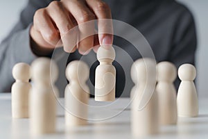 Man hand chooses wooden peg doll. leadership and business team creative thinking and human resources for teamwork or team player