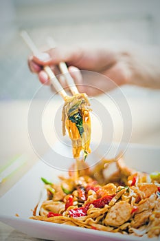 Man hand with chopsticks eat thai food closeup selective focus